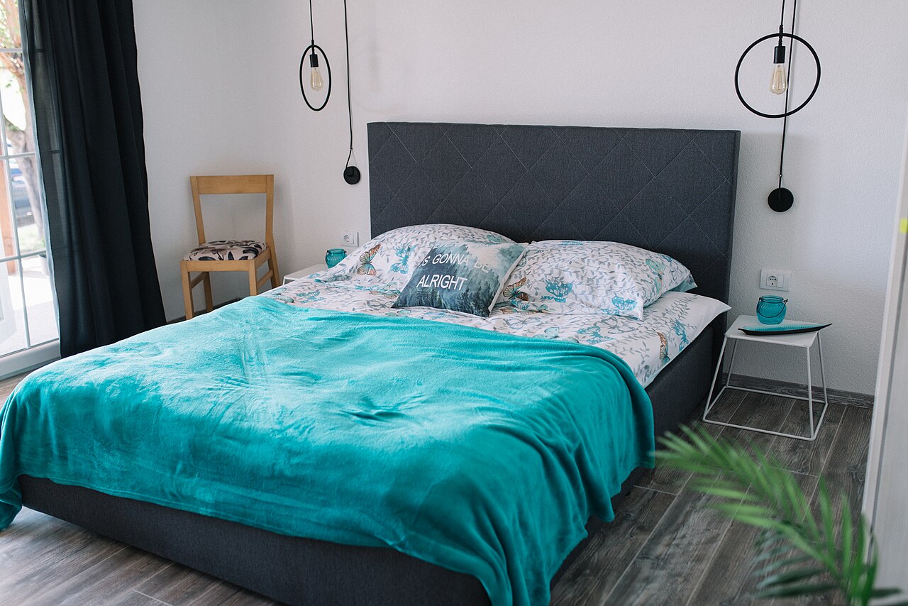 Upholstered bed frame with teal throw in a modern bedroom